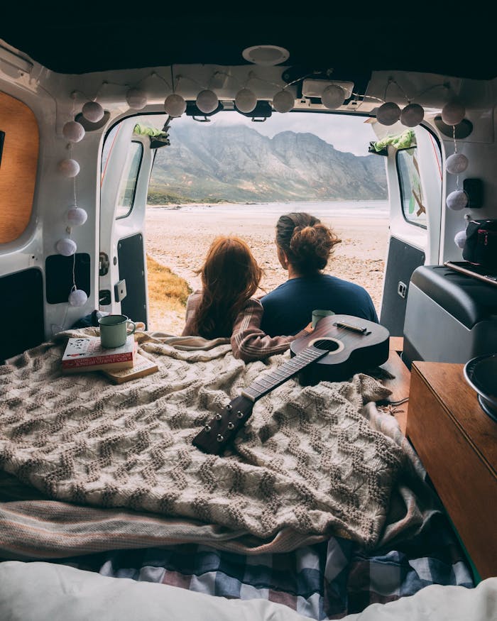 services-01 A couple enjoying a serene morning view from their camper van, surrounded by mountains.