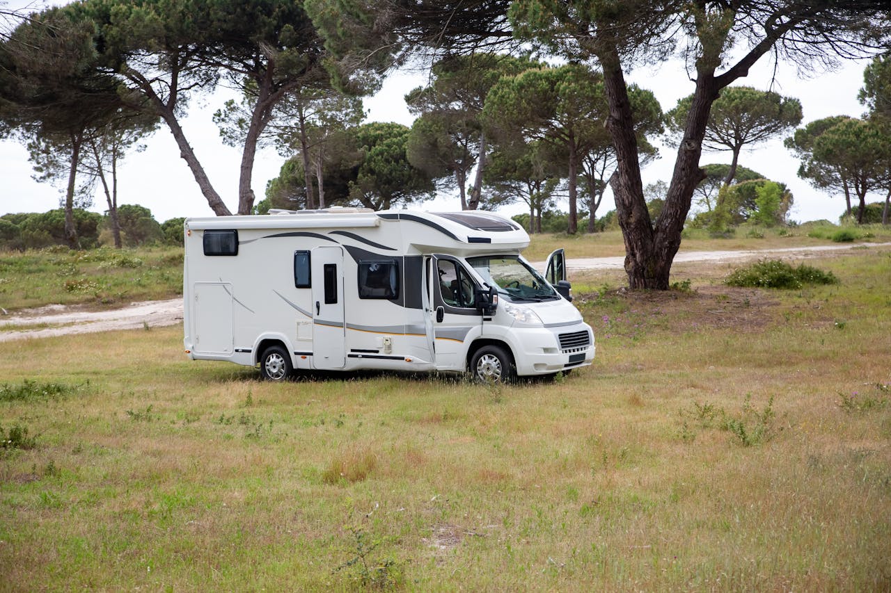 about-us-01 Captivating shot of a campervan amidst a serene field in Portugal, surrounded by trees.