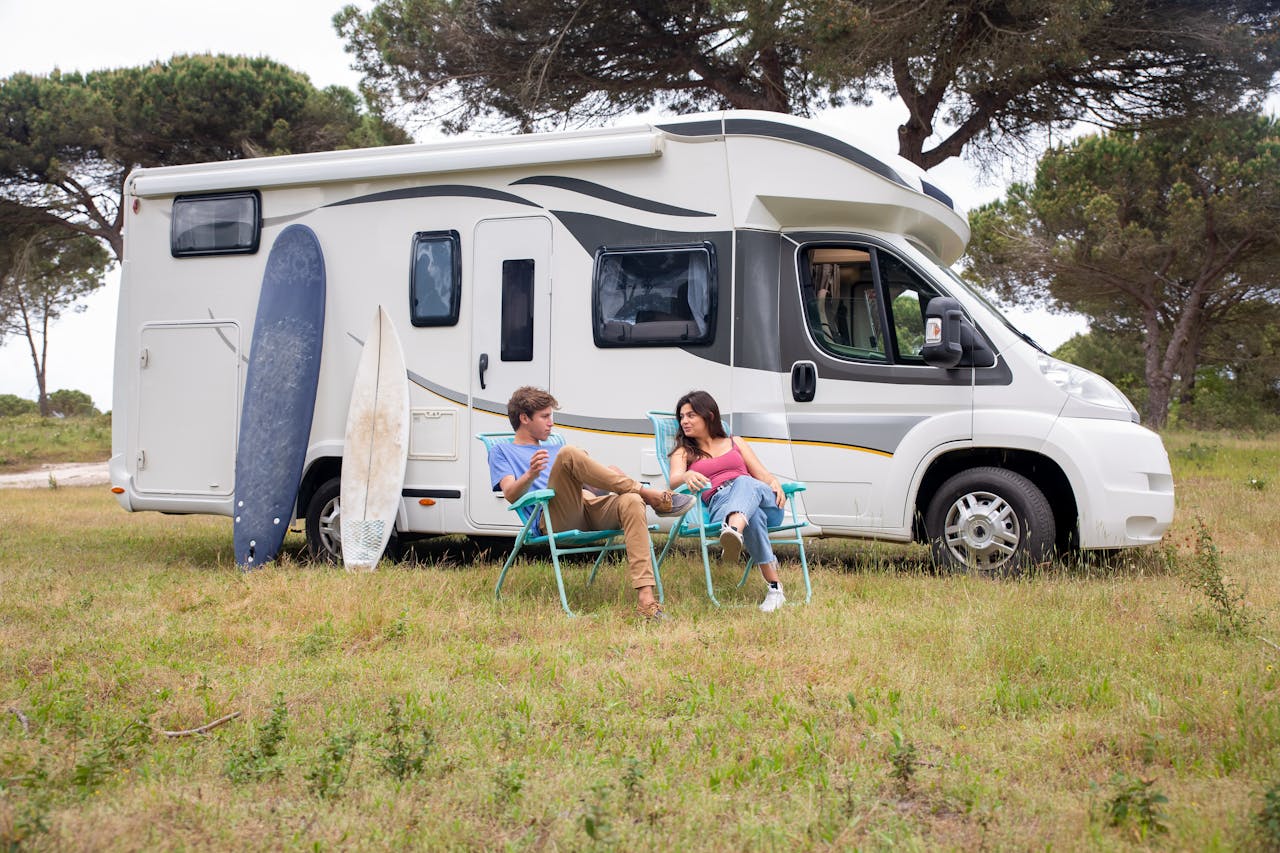 how-we-are A young couple enjoys leisure time by their campervan in a sunny outdoor setting.
