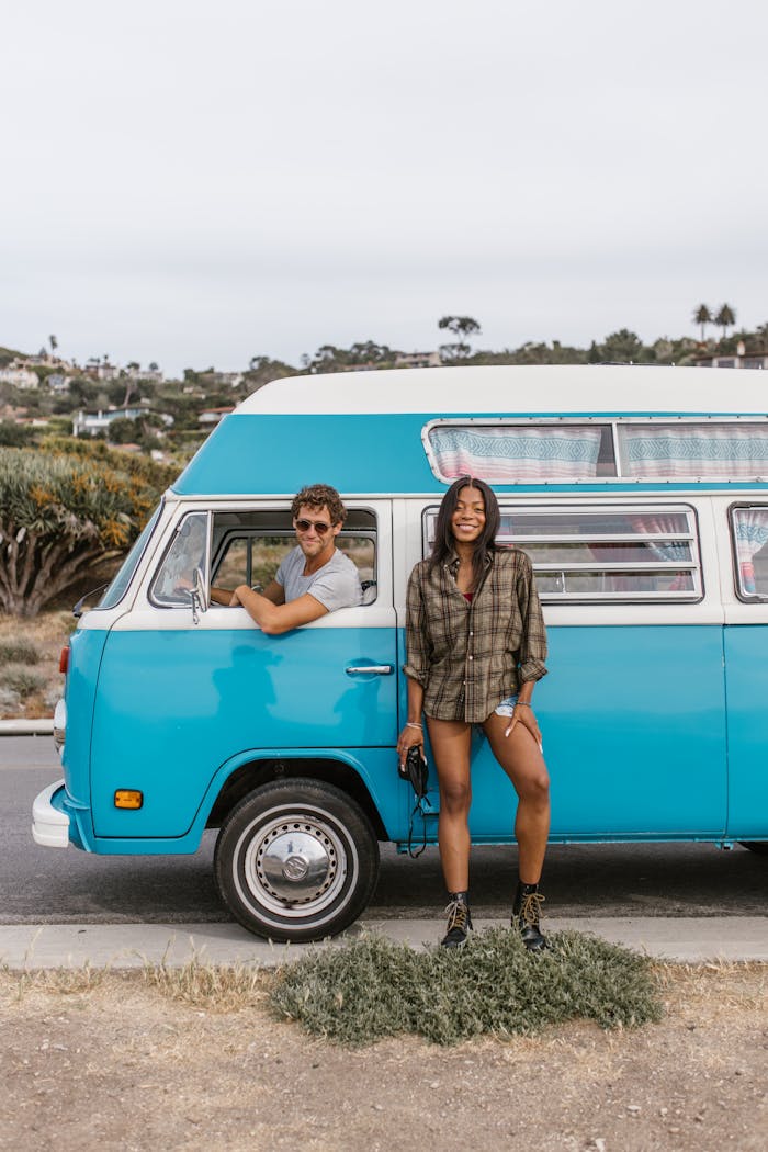 services-03 Smiling couple enjoying a road trip with a vintage blue campervan, embracing the van life lifestyle.